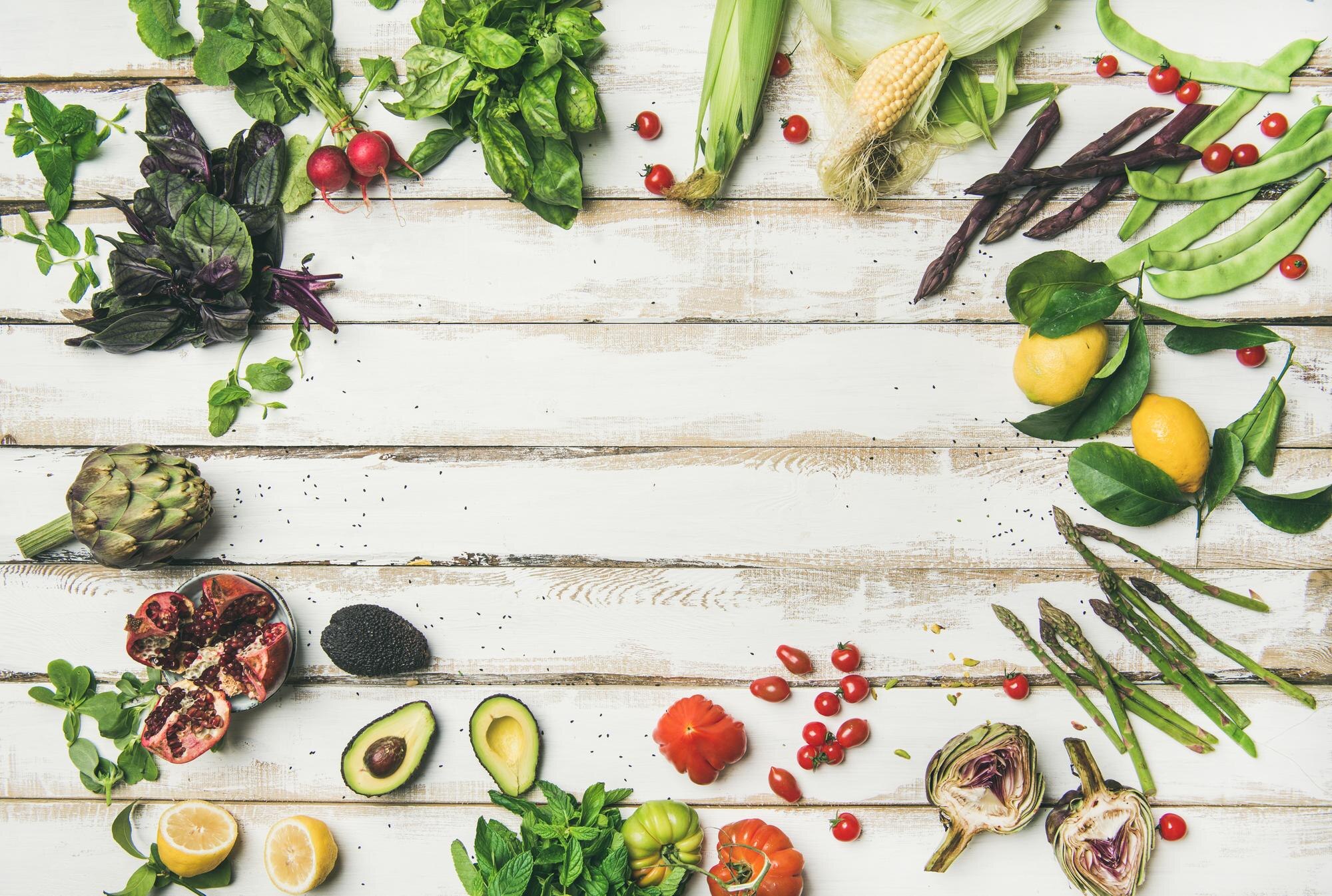 Colourful fresh vegetables and fruits arranged on a white wooden table β low-FODMAP friendly ingredients including kiwi, blueberries, carrots, and cucumber